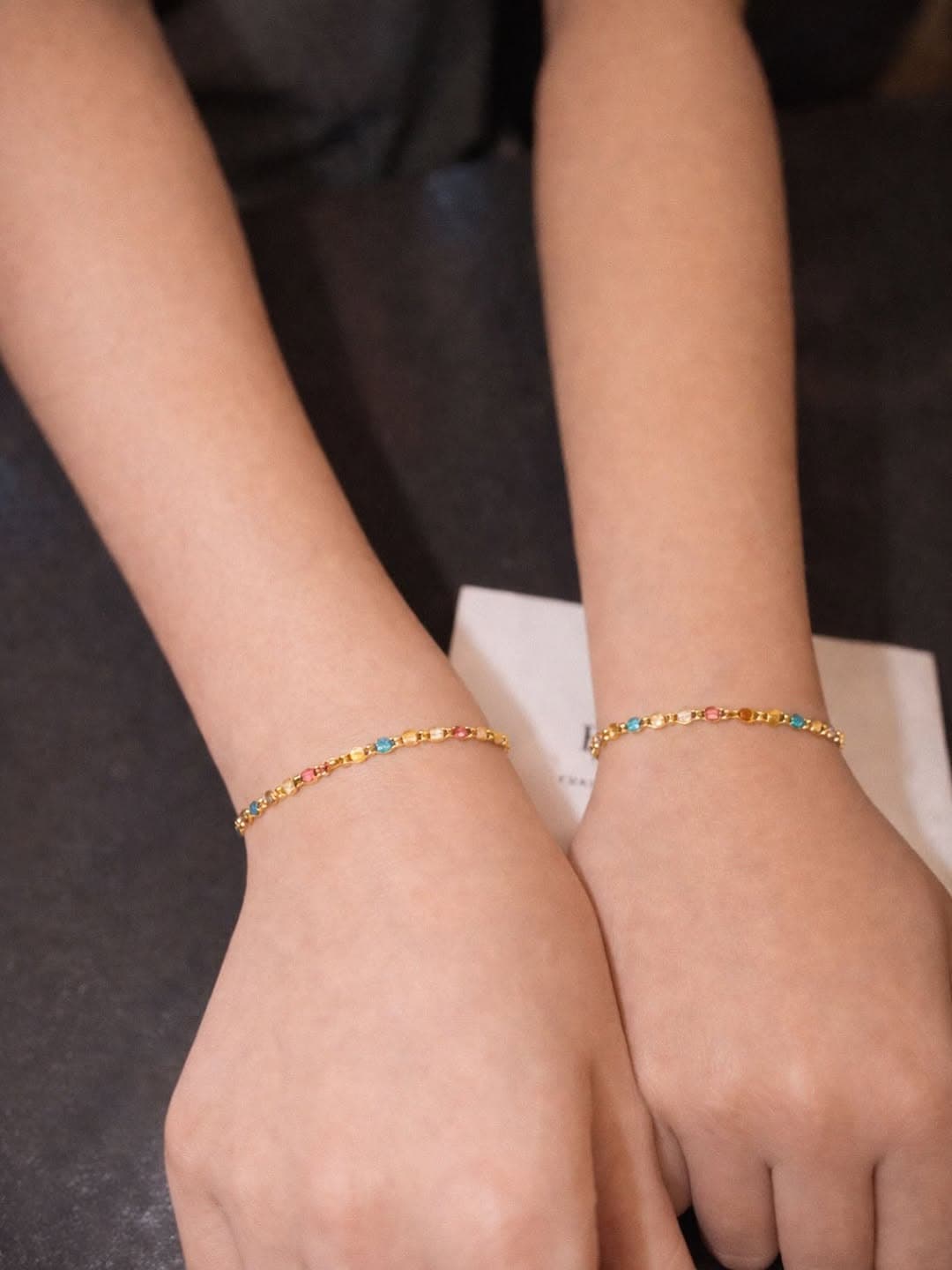 Matching colorful permanent bracelets on two wrists